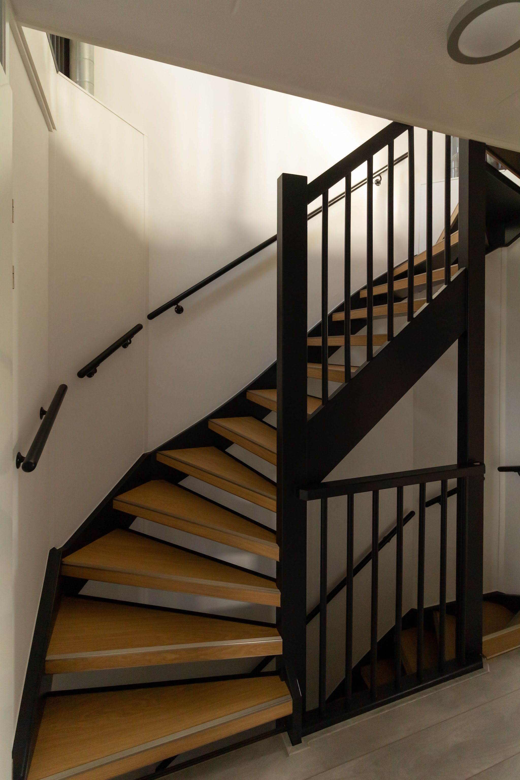 Trappenhuis met zwart gelakte trap en balustrade en witte wanden